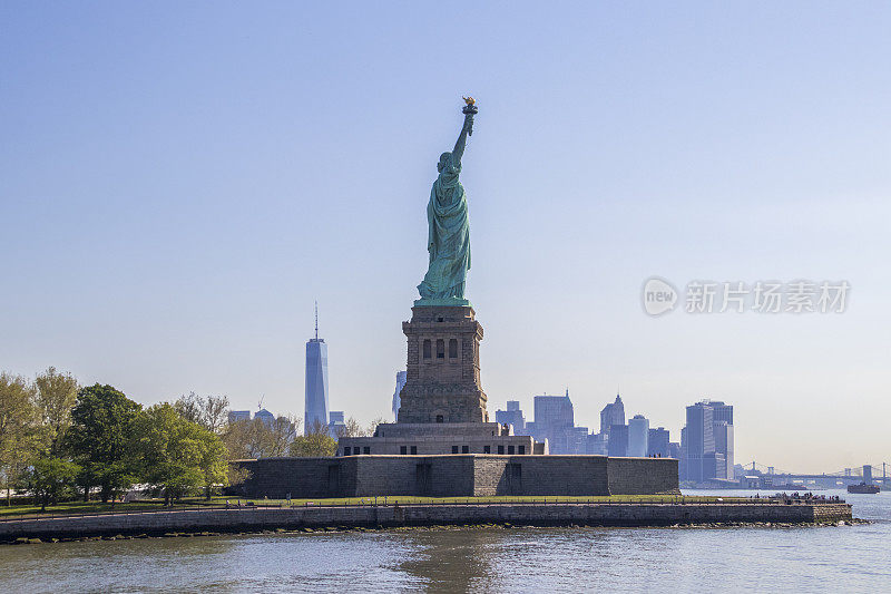 The Statue of Liberty (La Liberté éclairant le monde) and Manhattan skyscrapers at morning, Liberty Island, New York City, United States.